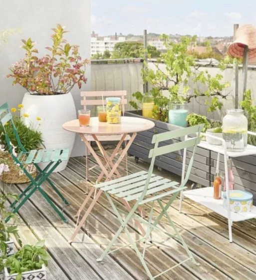 Balkon s růžovým a mátovým skládacím nábytkem a rostlinami