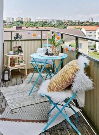 Balkon s tyrkysovým skládacím stolkem a dekoracemi s výhledem na město