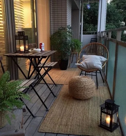 Balkon se skládacími stolky, ratanovým křeslem a lucernami