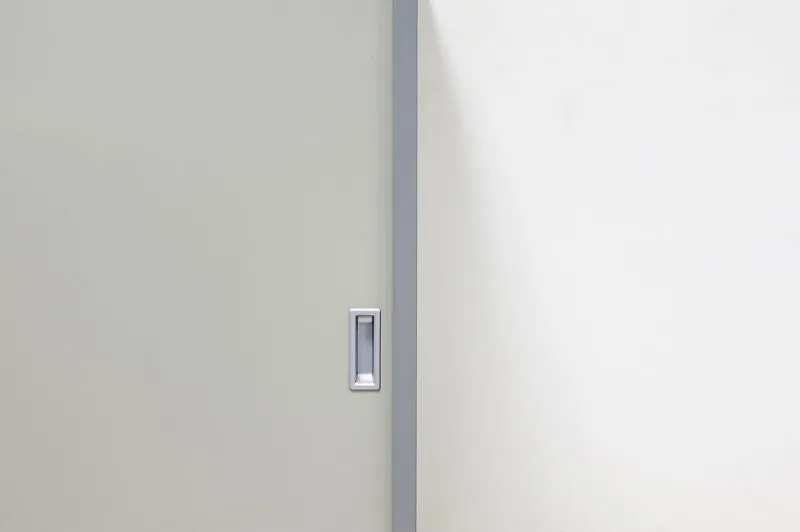 Detail madla na bílých posuvných dveřích vestavěné skříně