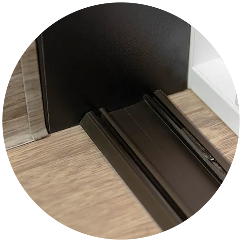Detail spodní kolejnice posuvných dveří osazené na podlaze skříně