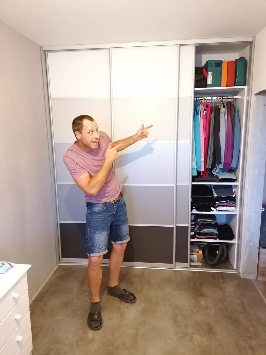 Vestavěná skříň s bílými posuvnými dveřmi a otevřeným úložným prostorem na oblečení